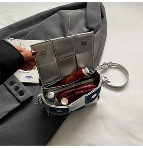 Macro view showing interior space of silver woven crossbody bag with phone and lipstick