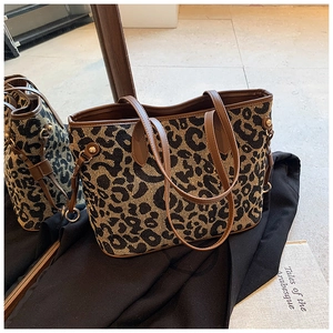 Detailed close-up of leopard print tote bag with brown leather handles and gold studs