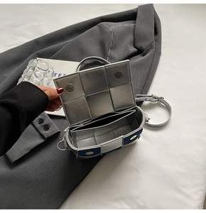 Detail view of woven leather texture and double magnetic closure on a small crossbody bag