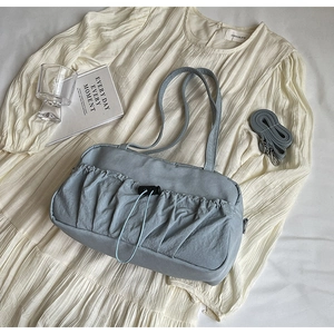 Detail of light blue pleated shoulder bag with drawstring showing texture and strap