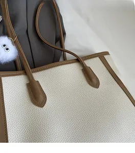 Dettaglio della borsa tote in pelle grana con bordo marrone e ciondolo peluche