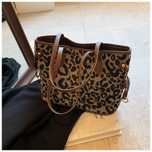Close-up of leopard print tote bag with brown leather handles and metal hardware detail