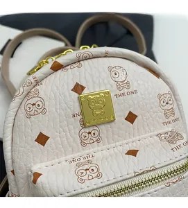 Close-up of beige lychee grain leather bag with cartoon bear prints and gold hardware