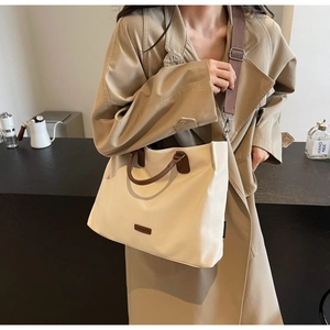 Detail of canvas tote bag with brown leather handles and adjustable crossbody strap