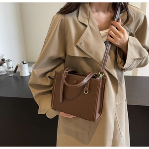Braune Lederhandtasche mit weißen Kontrastnähten und schmalem Schultergurt im Detail