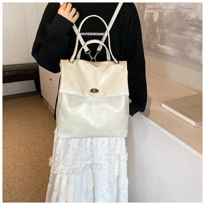 Detail of white geometric embossed leather backpack with a metallic twist lock closure