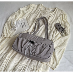 Detailed top view of grey pleated tote bag with drawstring on soft fabric backdrop