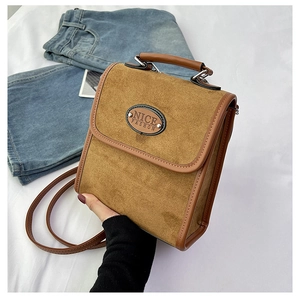 Close-up of brown suede rectangular handbag featuring Nice Fashion leather logo patch