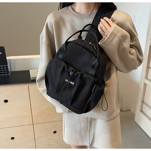 Detail of black nylon backpack featuring a drawstring pocket and durable top handles