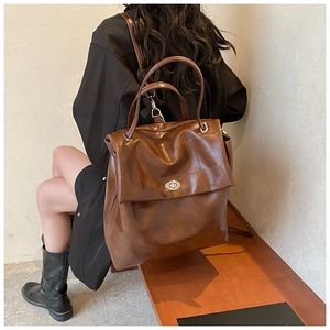 Detail of vintage brown leather backpack showing square stitching and silver twist lock