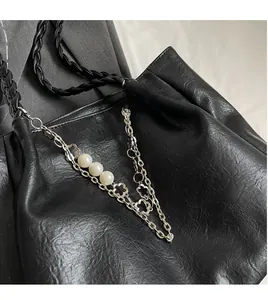 Close-up of black leather tote with silver chain, white pearls and floral charms