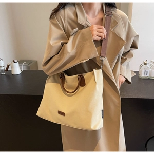 Detail of beige nylon tote bag with brown leather handles and adjustable shoulder strap