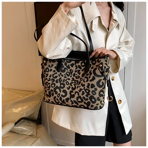 Detail of leopard print tote bag with black leather handle and golden metallic buckle