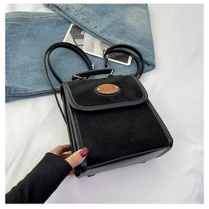 Detail of black faux suede backpack with faux leather trim and oval branded patch