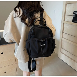 Detail of the black nylon backpack with a drawstring closure and a Youji Bear logo