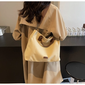 Detail of beige nylon tote bag featuring leather accents and adjustable wide shoulder strap