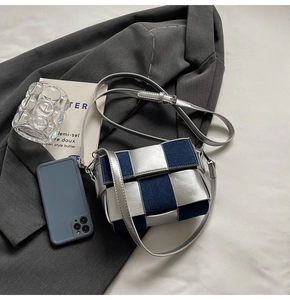 Detail of woven silver metallic leather and navy denim flap bag with silver buckle