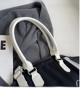Close-up of contrast leather handle and metal D-ring on a large nylon tote bag