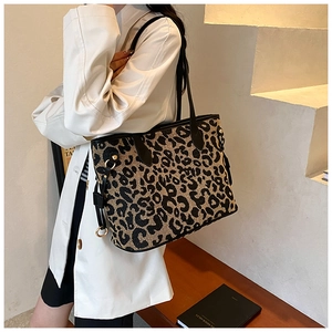 Detail of leopard print tote bag with black leather handles and gold metal hardware