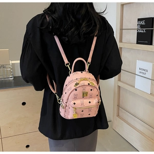Detail of pink backpack with cartoon bear pattern and gold chain straps in lifestyle setting