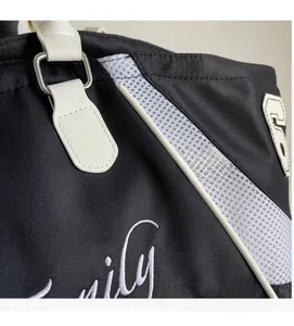 Detail of black canvas tote featuring white mesh stitching and embroidered script