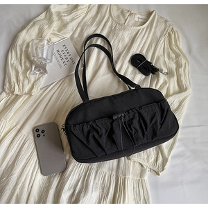 Detail of black pleated shoulder bag with adjustable strap on a minimalist background
