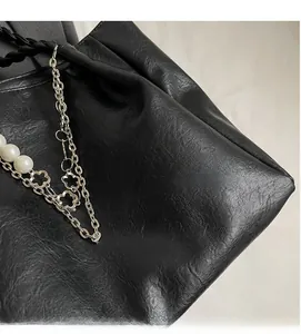 Detail of high-quality black PU leather tote with silver chain and pearl flower charms