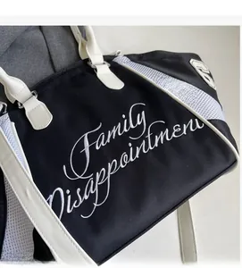 Close-up of black canvas tote bag with white leather trim and side mesh detail