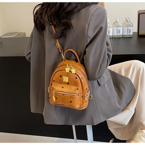 Detail of a brown leather mini backpack featuring cartoon bear patterns and gold hardware