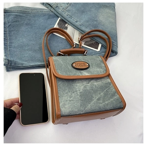 Detail of vintage denim mini backpack with leather trim shown next to a smartphone