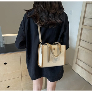 Detail einer beigen Umhängetasche aus genarbtem Leder mit braunen Kanten an einem Model