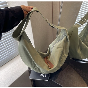 Detail showing avocado green nylon crescent bag with silver buckles and leather pullers
