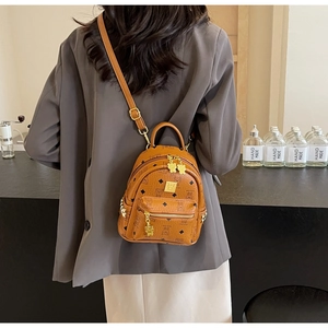 Detail of a brown patterned mini backpack with gold hardware worn as a stylish crossbody bag