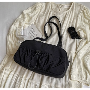 Detail of black pleated shoulder bag with drawstring pocket and detachable strap