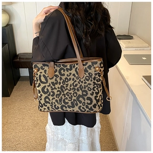 Detail shot of a large leopard print tote bag with leather straps on a female model
