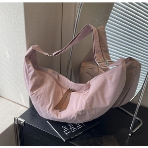 Detail of a light pink nylon dumpling bag with adjustable strap and leather zipper puller