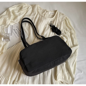 Detail view of black canvas shoulder bag with dual adjustable straps and silver metal hooks