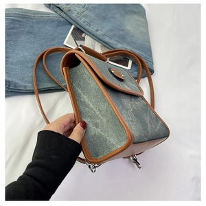 Detailed close-up of retro denim handbag with brown leather trim and metal NICE emblem