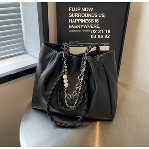Detail of black pleated tote bag featuring woven handle and pearl metal chain decoration
