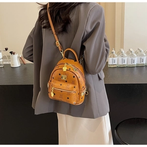 Detailed back view of a brown leather mini backpack with bear monogram on a female model