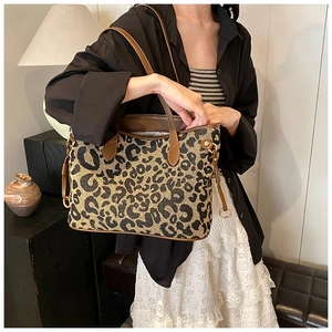 Close-up of leopard jacquard tote bag featuring brown leather handles and gold metal rings
