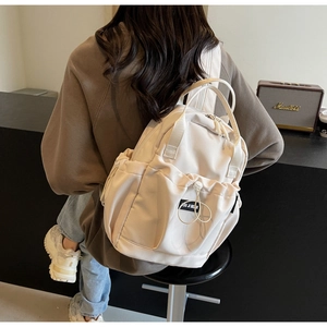 Detailed back view of a beige nylon backpack with adjustable straps and drawstring front pocket