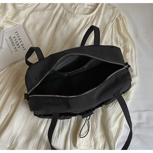 Detail of black pleated shoulder bag showing interior pocket and silver zipper closure