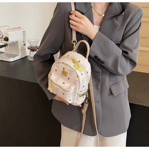 Detailed view of mini cream backpack with bear print and gold zipper on model