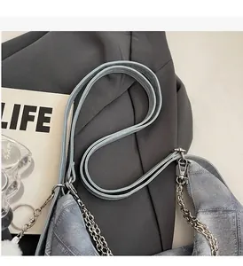 Detail of light blue denim crescent tote with silver chain and white plush charm