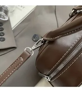 Detail of brown leather bowling bag showing silver hardware and white contrast stitching
