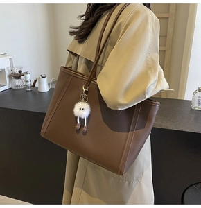 Dettaglio borsa tote in pelle marrone scuro con charm a mostriciattolo di peluche