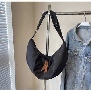 Detail of nylon dumpling bag featuring brown leather zipper pulls and adjustable strap