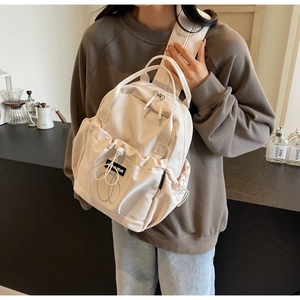 Close-up of lightweight off-white nylon backpack with front drawstring pocket and logo detail