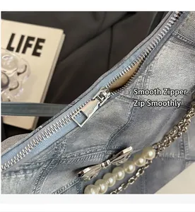 Detailed shot of smooth silver zipper and metallic bow charm on denim tote bag